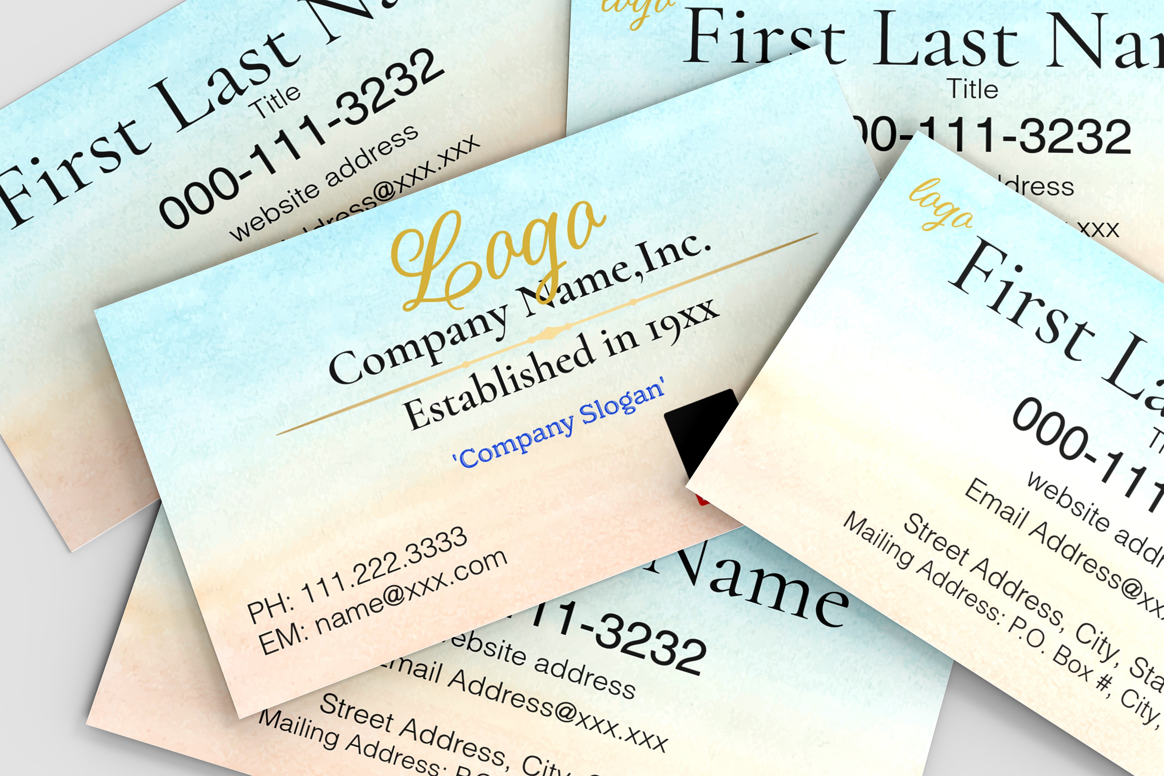 A close-up, angled view of several business cards fanned out. The cards have a soft watercolor gradient background transitioning from pale blue at the top to warm beige at the bottom.