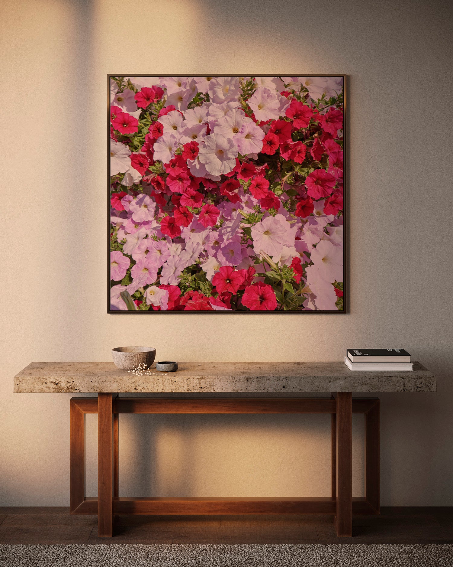 A framed floral wall art print featuring vibrant pink, red, and white flowers with green leaves, displayed above a rustic wooden console table against a warm beige wall.
