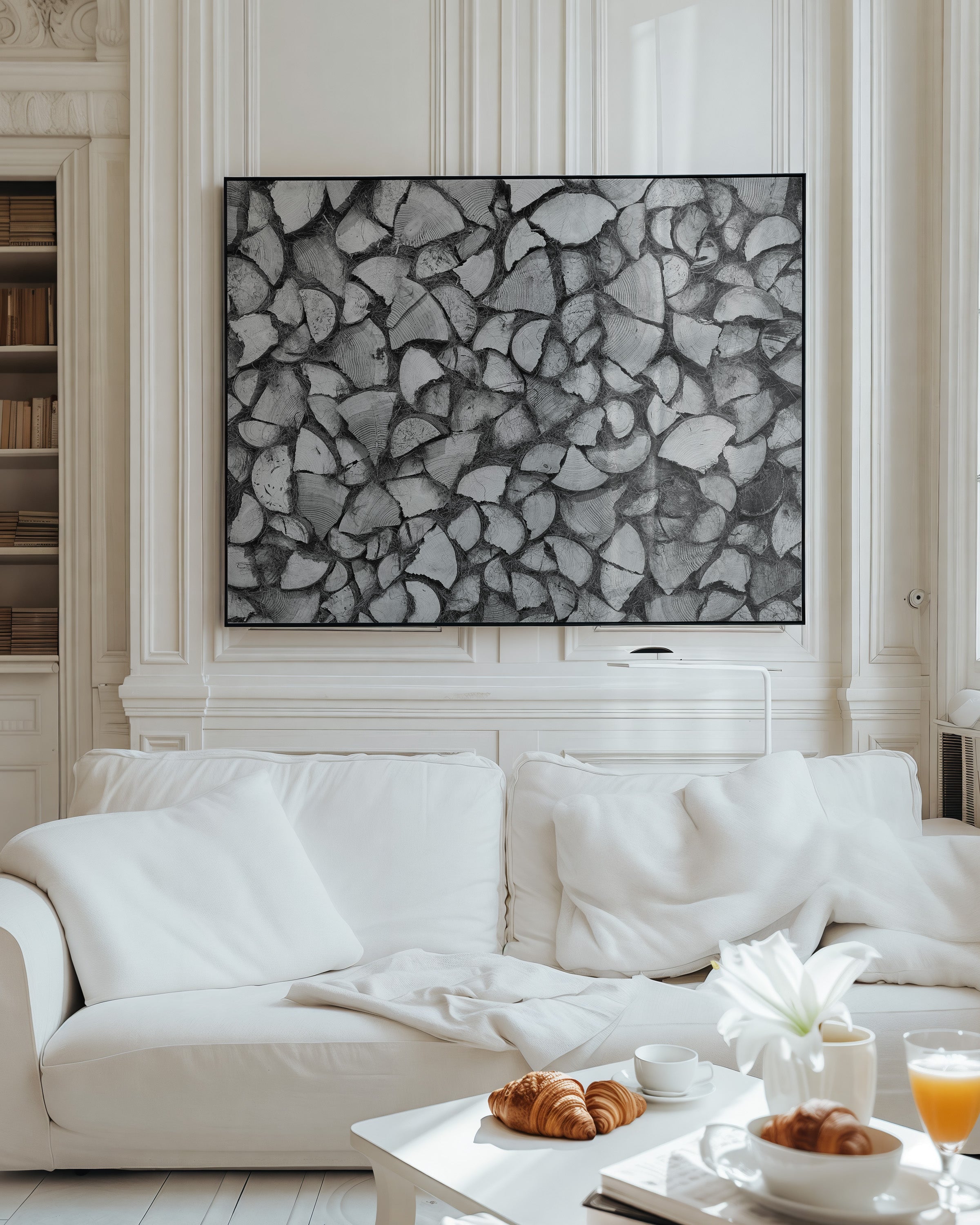 A large black and white abstract wall art print featuring a cracked stone pattern, displayed in a classic white living room above a white sofa with breakfast items on a coffee table.