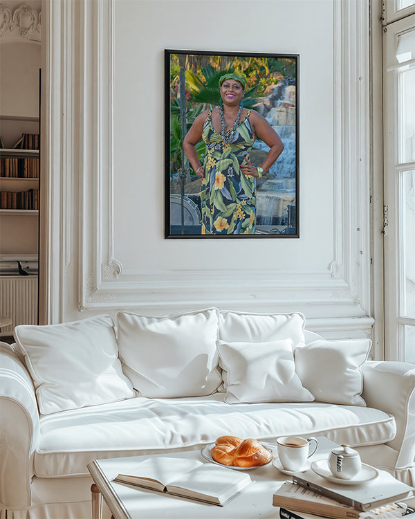 A framed vertical art print of a woman in a green and yellow floral dress, displayed on a white wall above a white sofa in a bright, elegant room.