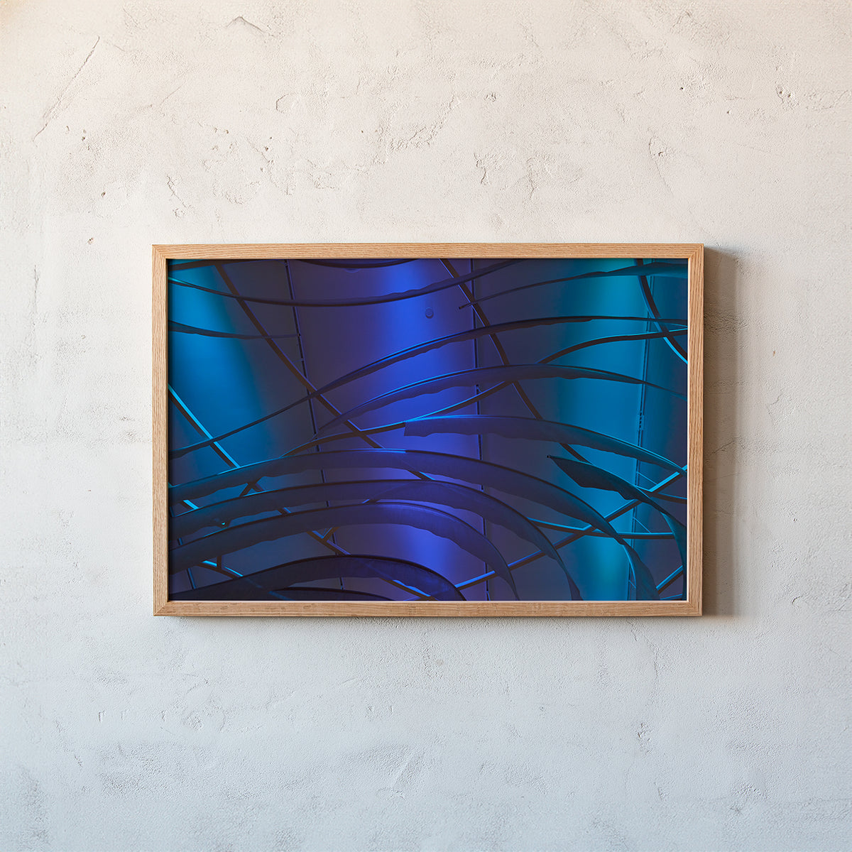 A framed abstract art print featuring blue and purple curved lines on a textured light gray wall.