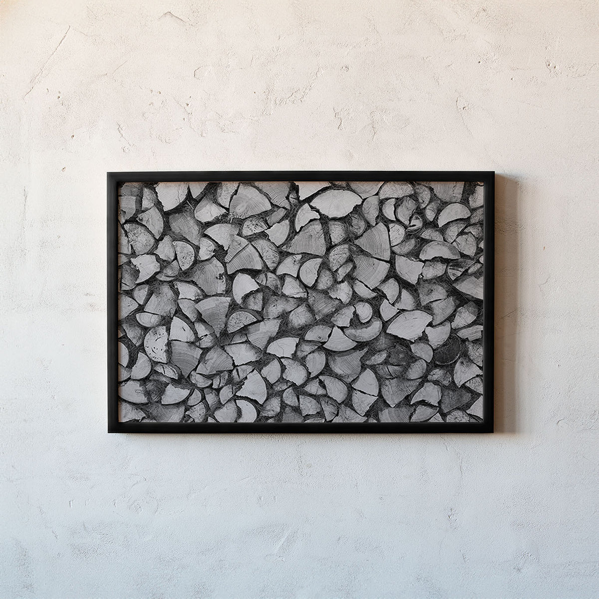 A framed black and white art print depicting a textured pattern of overlapping stone or wood fragments, mounted on a light textured plaster wall.