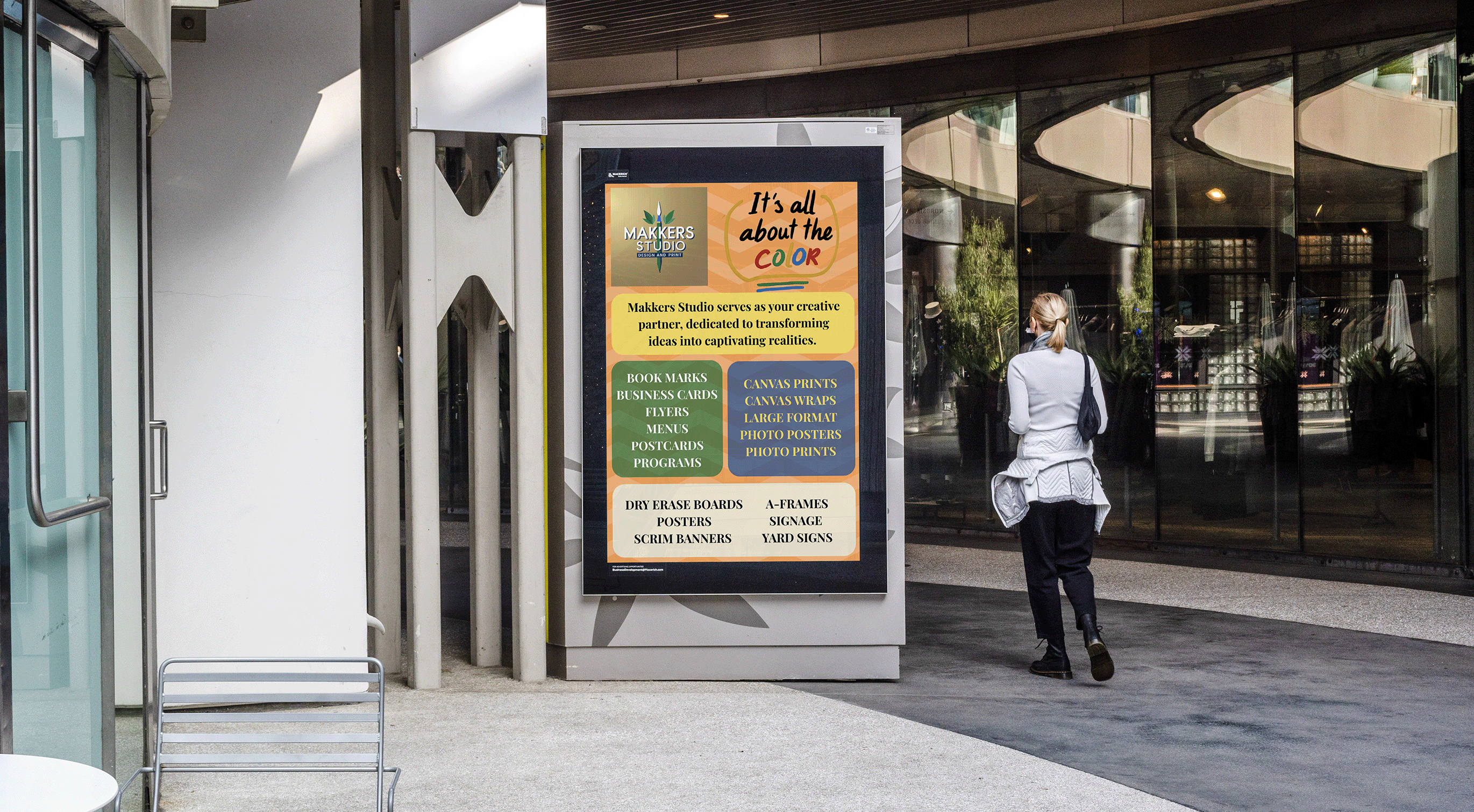 Person walking past a digital display with colorful text in an urban setting