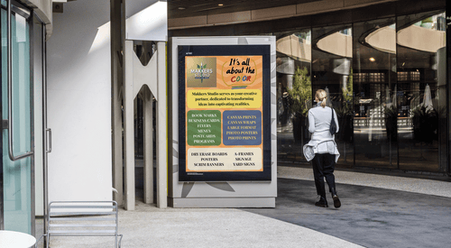 Person walking past a digital display with colorful text in an urban setting