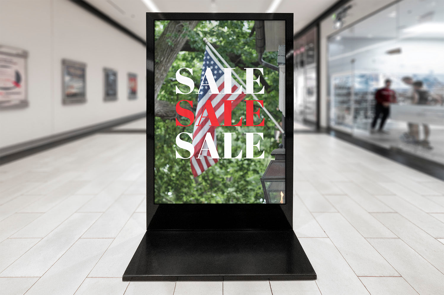 Digital display in a shopping mall with 'SALE' text and American flag.