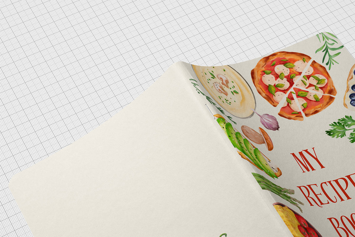An open recipe book with a cream-colored cover decorated with colorful illustrations of pizza, pasta, vegetables, and red text reading 'MY RECIPE BOOK', placed on a white graph paper background.
