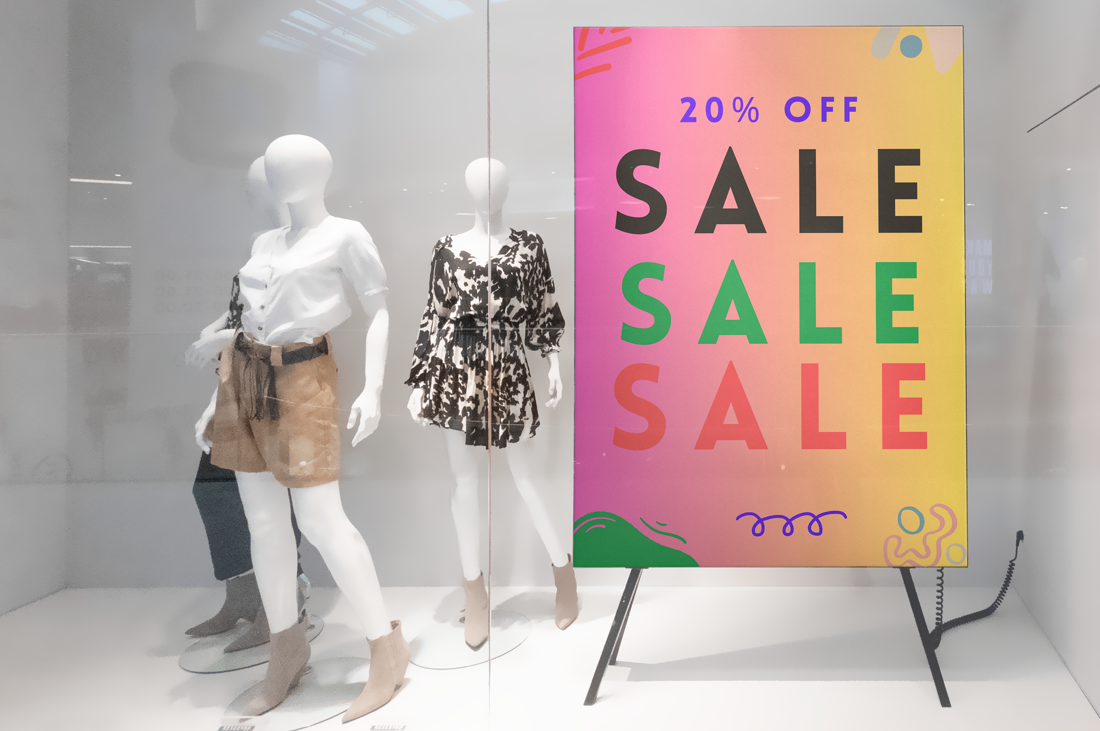 Mannequins in a store window with a 'SALE' sign advertising a 20% discount.