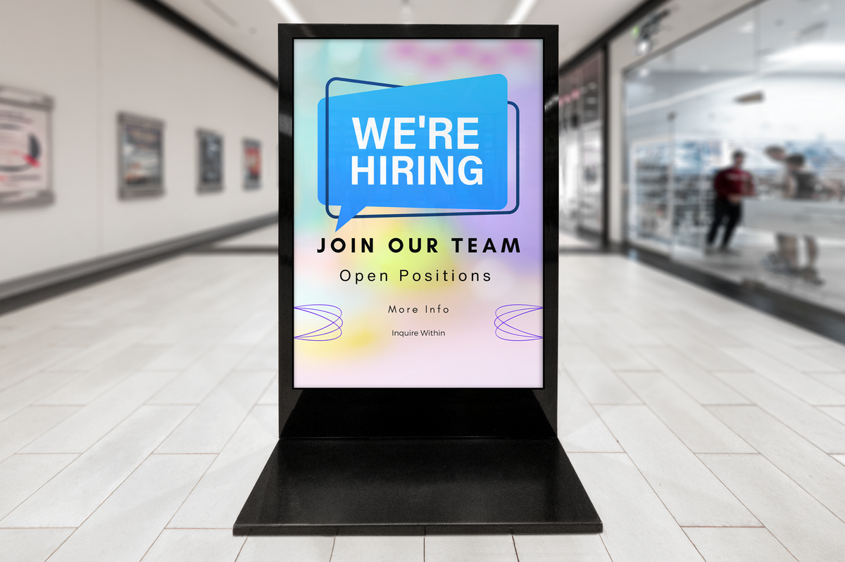 Digital display board in a shopping mall with 'We're Hiring' message.